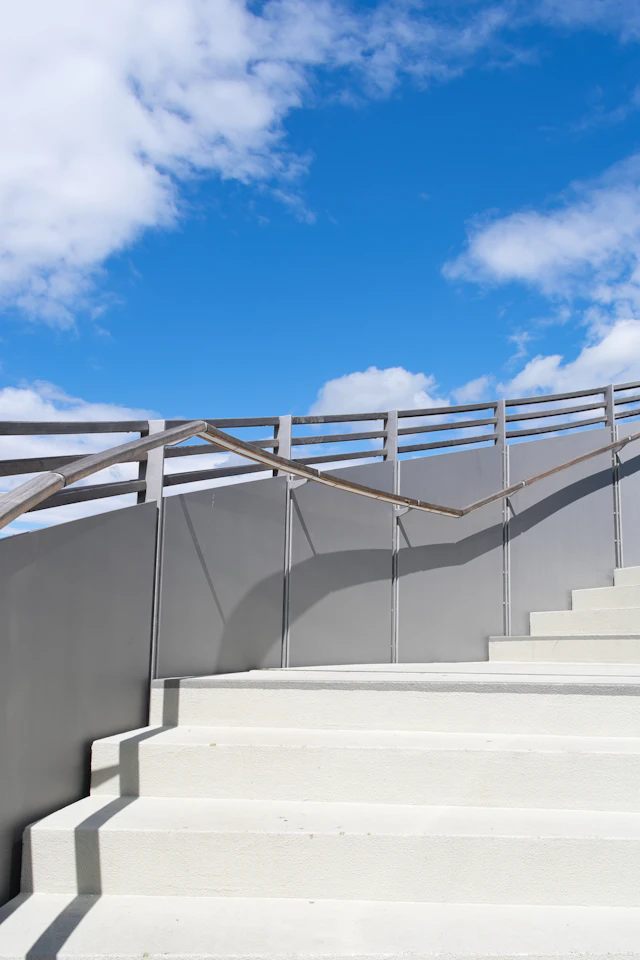 Sunlit architectural stairs rising toward a blue sky.